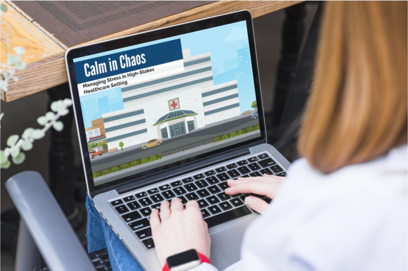 A person working on a laptop that shows the title screen of Calm in Chaos, a video on managing stress in healthcare
